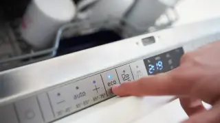 Palec naciska przycisk "eco" na panelu zmywarki, wybierając program oszczędzający wodę. Zastanawiasz się, ile wody zużywa zmywarka w tym trybie?