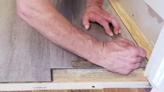 Ręce układają panele winylowe, tworząc płynne łączenie paneli z płytkami.